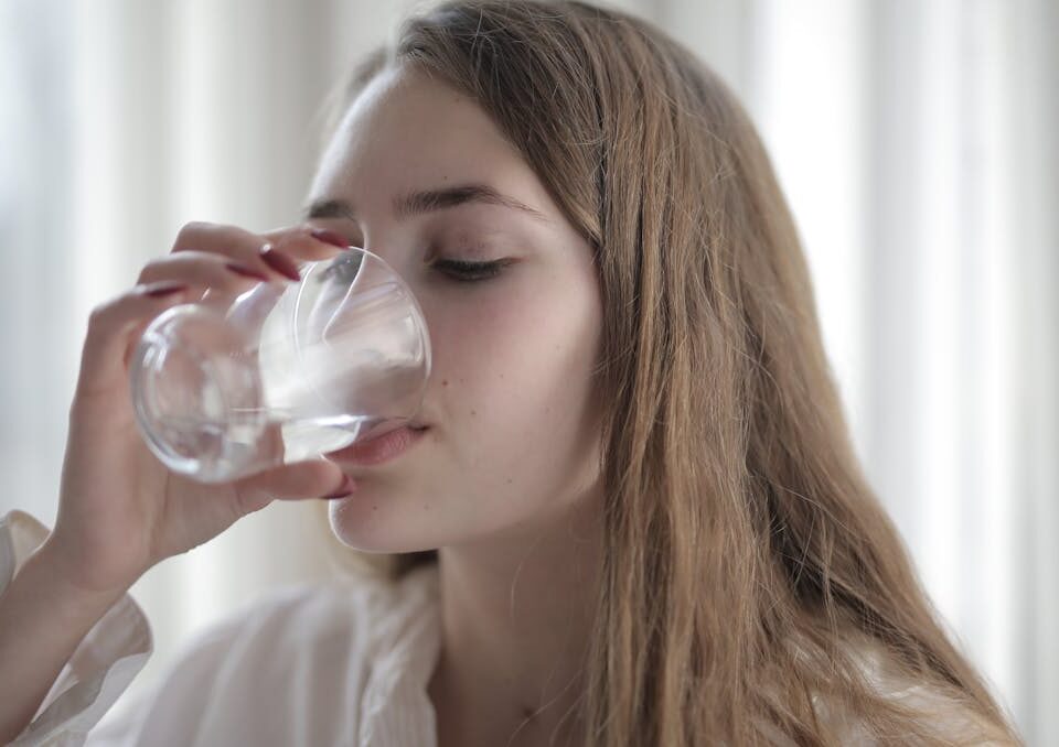 Hidratação: benefícios, estratégias e dicas práticas mulher tomando agua para hidratação