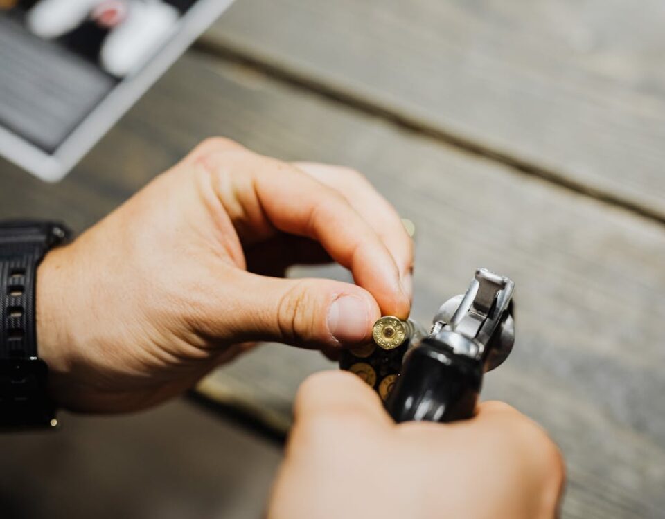 Como a segurança pessoal com armas pode influenciar o bem-estar Hands of a Person Holding a Gold Bullet and a Pistol
