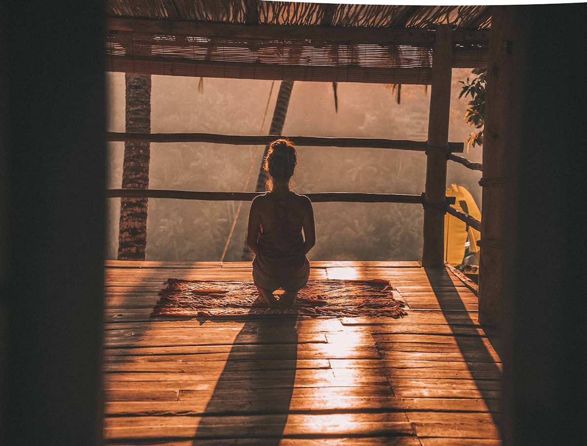 Estoicismo e bem-estar: viver melhor com menos preocupações woman meditating on floor with overlooking view of trees
