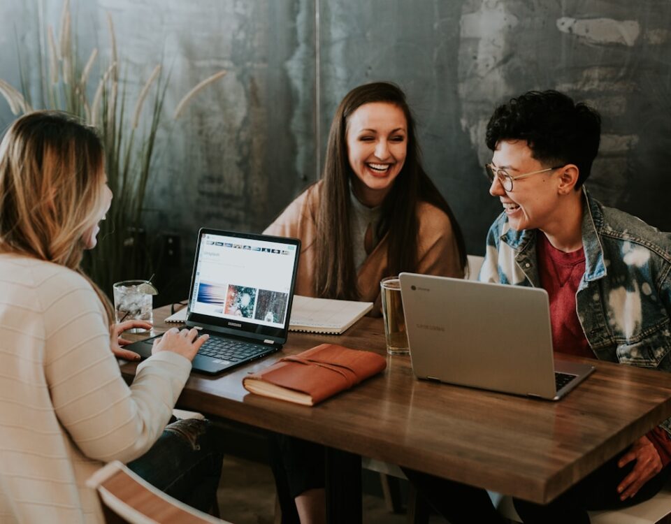 Chatbots no atendimento: como manter a humanização nas interações three people sitting in front of table laughing together