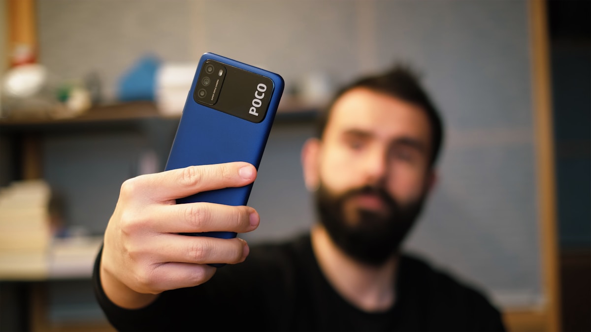 Como o marketing digital pode melhorar seu bem-estar financeiro man in black crew neck shirt holding blue samsung android smartphone