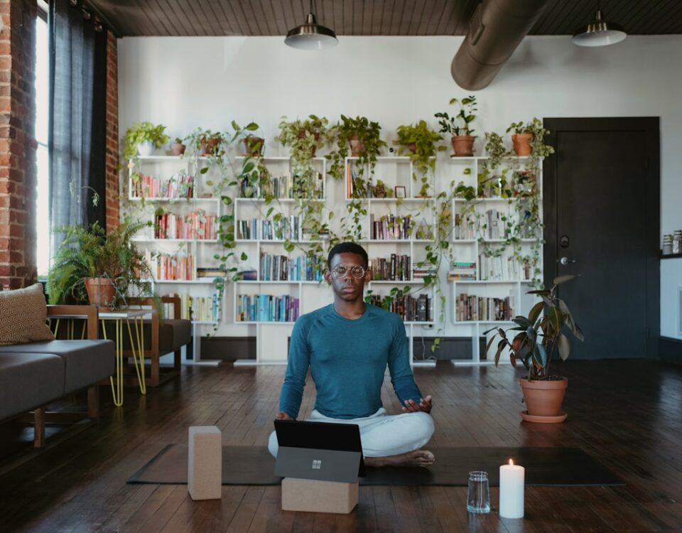Cursos livres de bem-estar: melhore sua qualidade de vida a man sitting on a yoga mat with a laptop in front of him