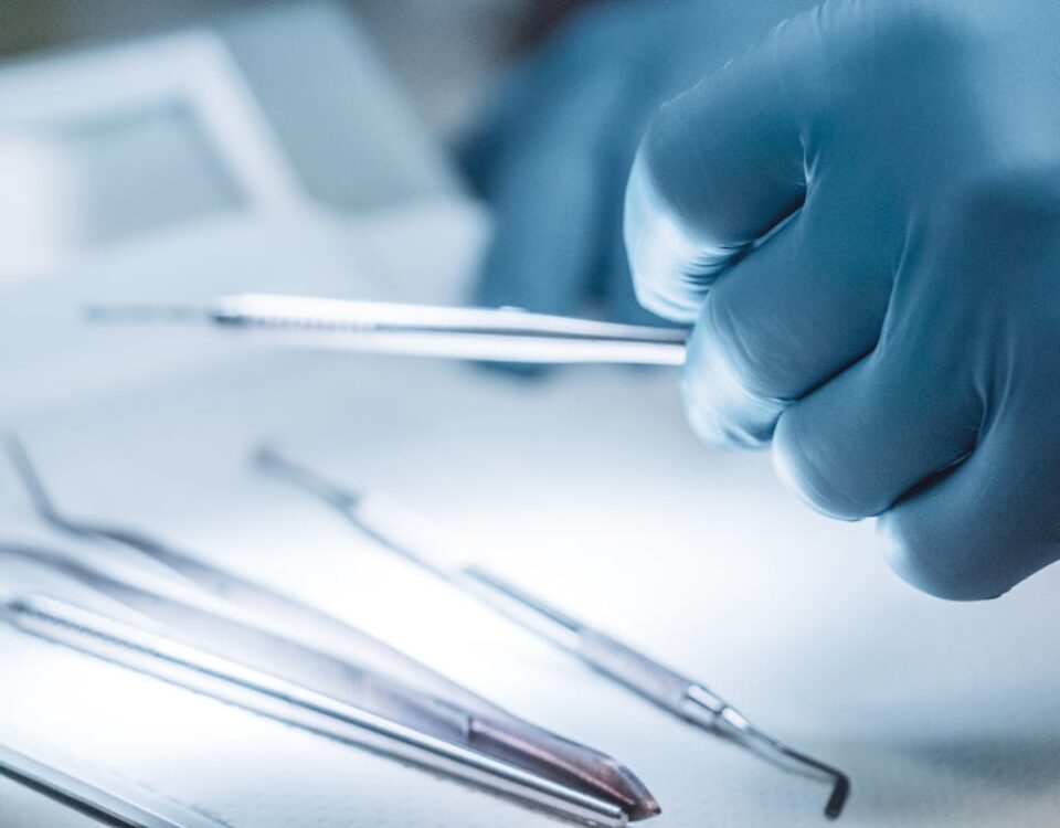 Luvas Descartáveis: Quando Trocar e Qual o Impacto na Segurança do Paciente Close-up of a surgeon's gloved hand holding surgical instruments in a sterile setting.