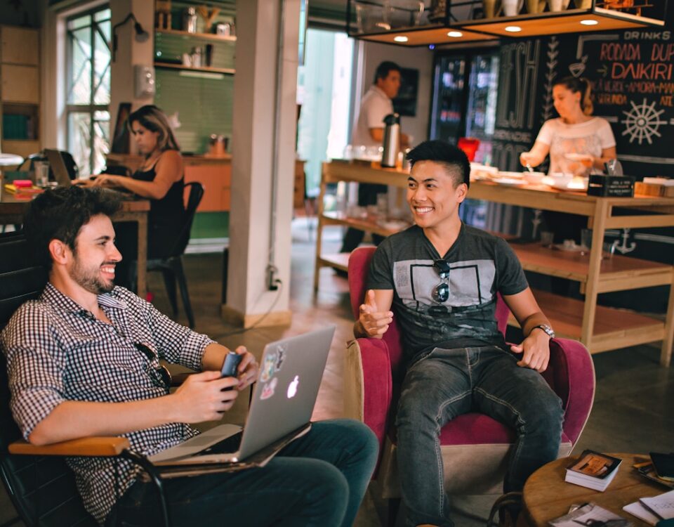 Como o bem-estar influencia o sucesso de um empreendedor two men laughing white sitting on chairs
