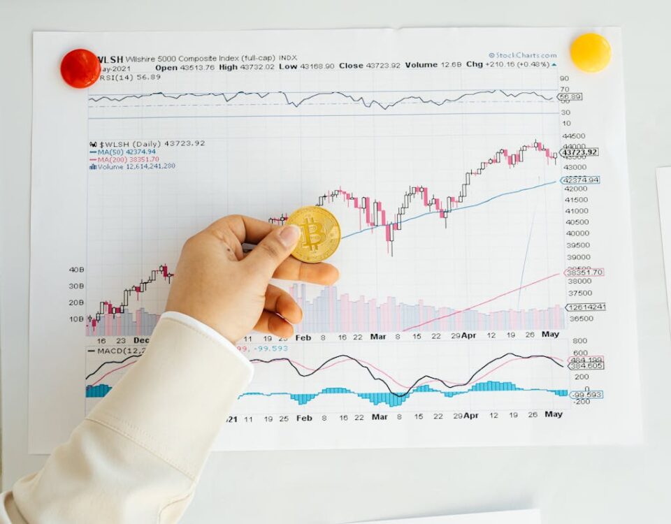 Person Holding A Bitcoin With Stock Chart Report On Wall