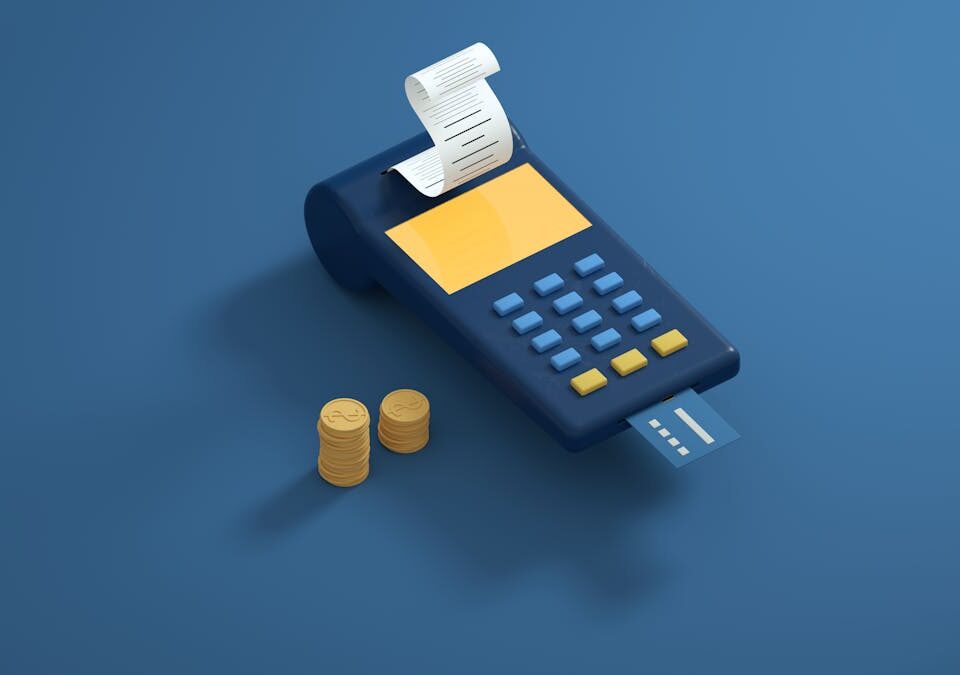 Cashback no cartão: Como economizar nas despesas diárias Blue payment terminal with receipt and gold coins on a blue background, symbolizing modern transactions.