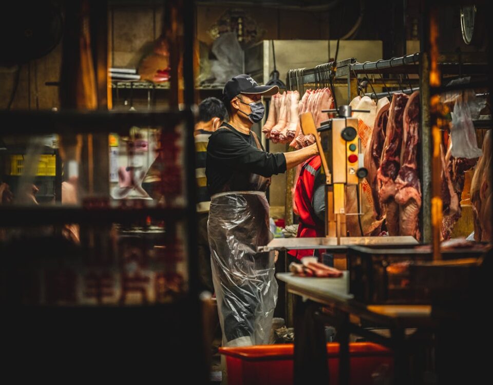Impacto de alimentos mal armazenados na saúde Butchers working in a Miaoli, Taiwan meat market, handling fresh pork.
