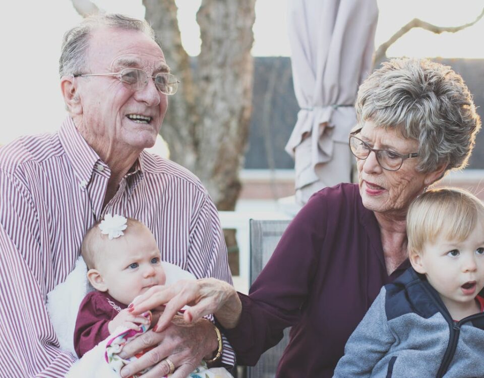 Estratégias invisíveis que melhoram sua qualidade de vida Grandparents spending joyful moments with their grandchildren in an outdoor setting, captured candidly.