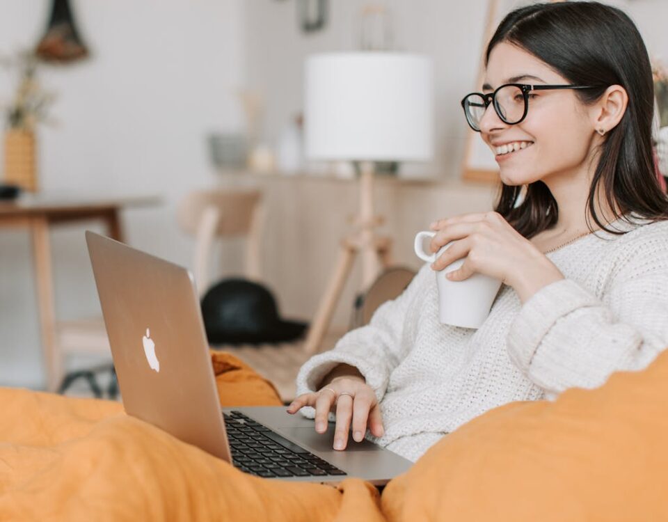 Woman enjoying a cozy moment with a laptop and coffee in a modern interior setting.