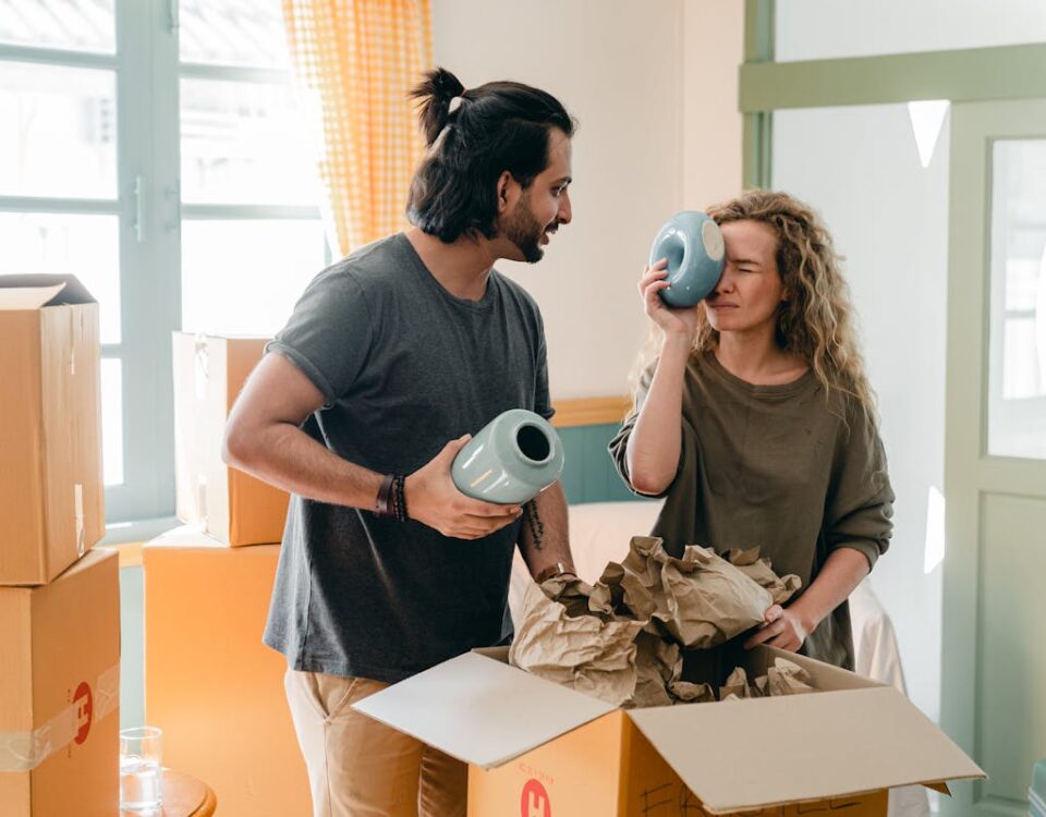 A influência dos souvenires no bem-estar emocional A happy couple unpacks boxes, enjoying their new home with laughter and excitement.
