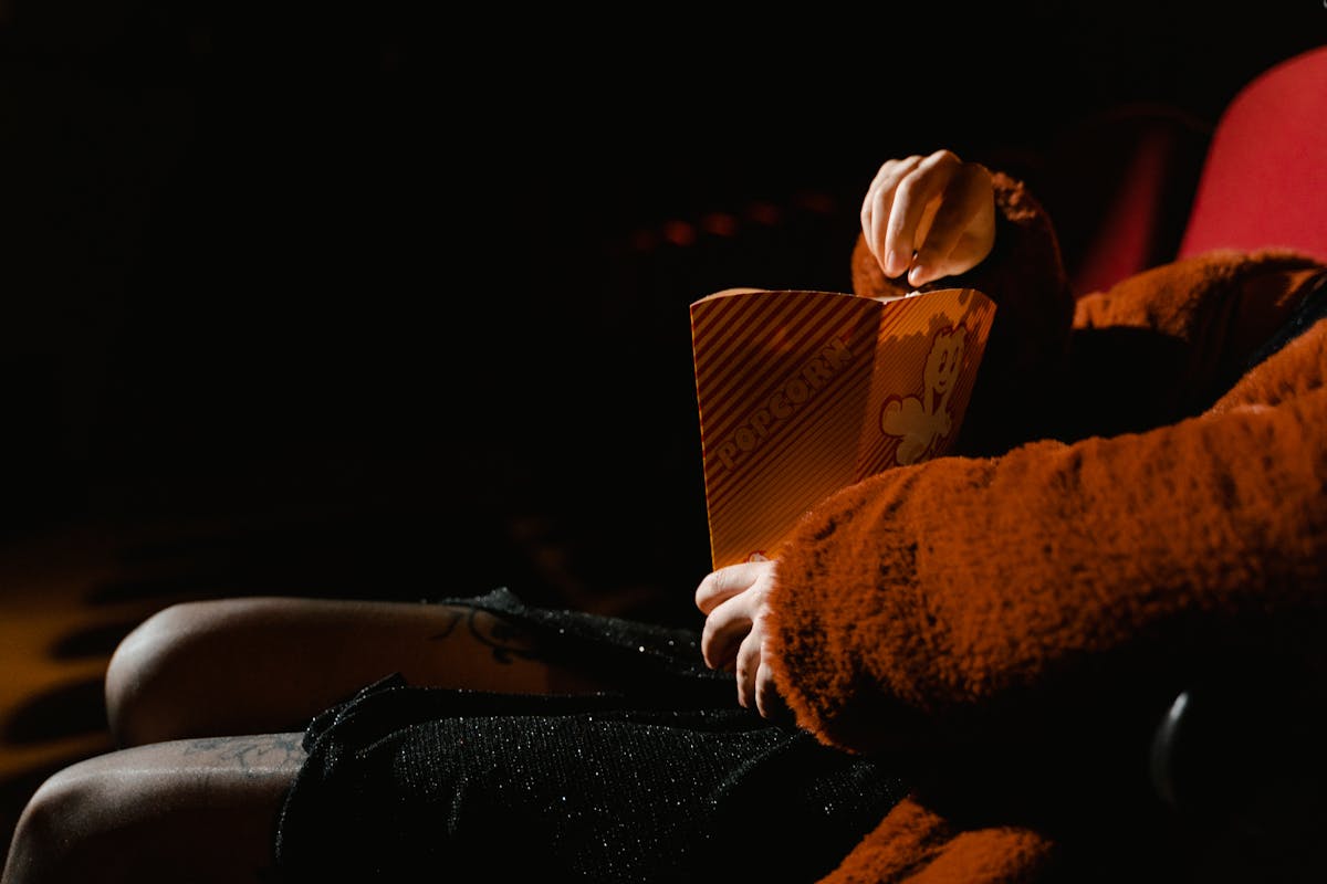 A person enjoying popcorn during a movie at an indoor cinema, sitting comfortably.