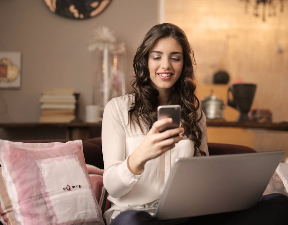 Como painéis SMM ajudam no equilíbrio entre vida e trabalho A woman enjoying leisure time using her smartphone and laptop in a cozy living room.