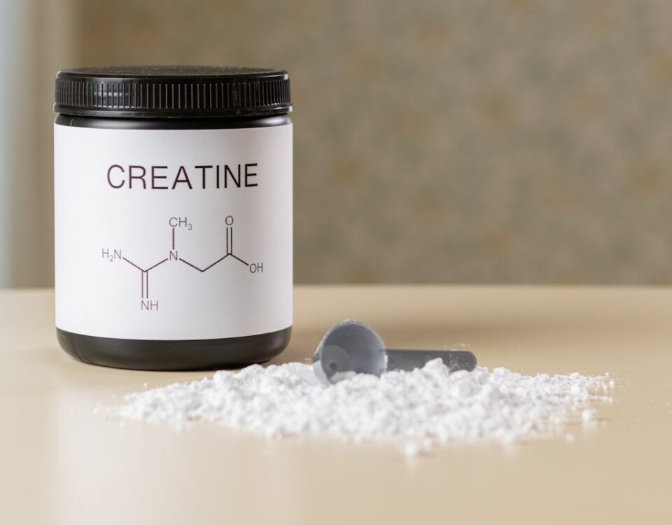 a bottle of creatine next to a spoon on a table