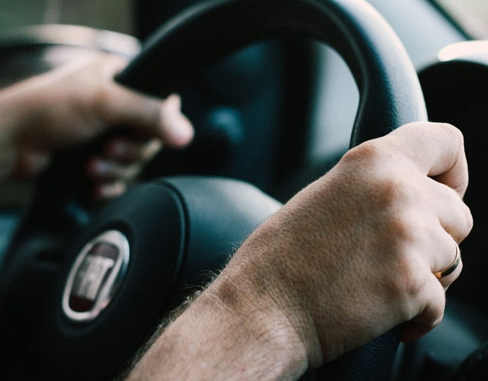 Cuidados para manter a calma no exame de direção Hands firmly gripping a car steering wheel, ready to drive.
