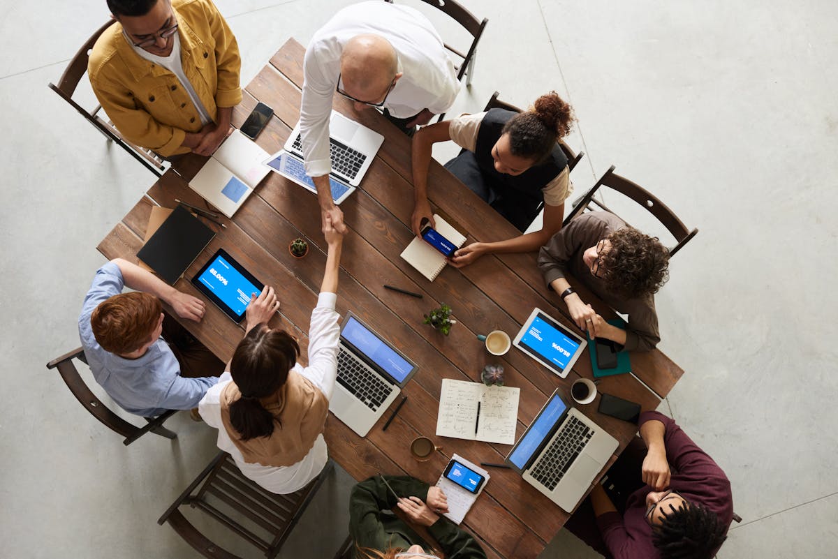 Bem-estar no trabalho: desafios em empresas de TI Top view of a diverse team collaborating in an office setting with laptops and tablets, promoting cooperation.