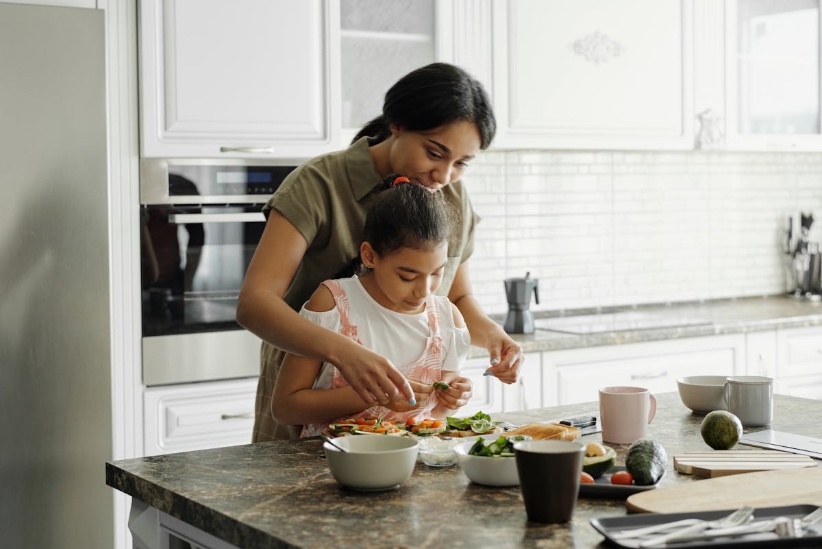 Cozinhar pode ser uma terapia? A mom and daughter share a bonding moment while preparing a healthy lunch together in the kitchen.