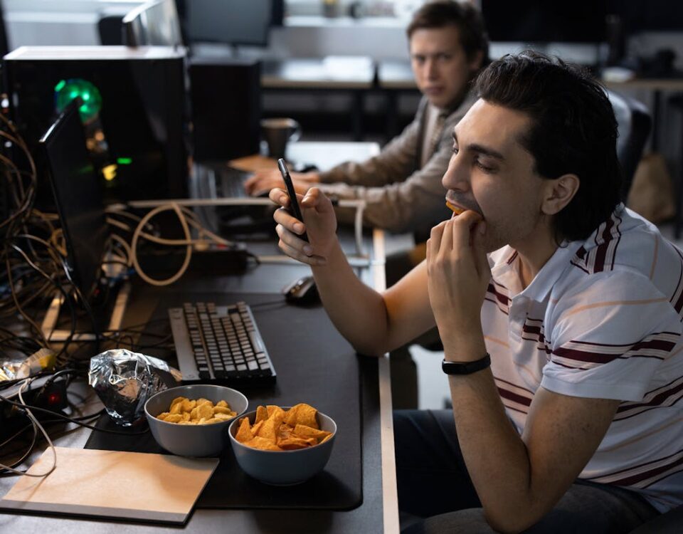 Bem-estar no trabalho: desafios em empresas de TI Men taking a break from coding, enjoying snacks at a tech startup office.