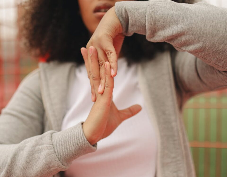 Dicas de alongamento para quem dirige por muitas horas Close-up of a woman stretching hands outdoors wearing a gray jacket, perfect for lifestyle and fitness themes.