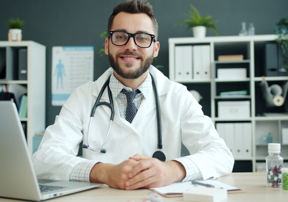 Doctor wearing a stethoscope sits at a desk.