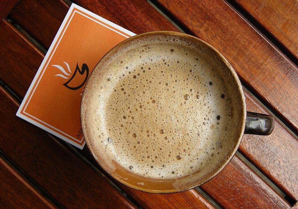 Xícara de café com espuma sobre mesa de madeira