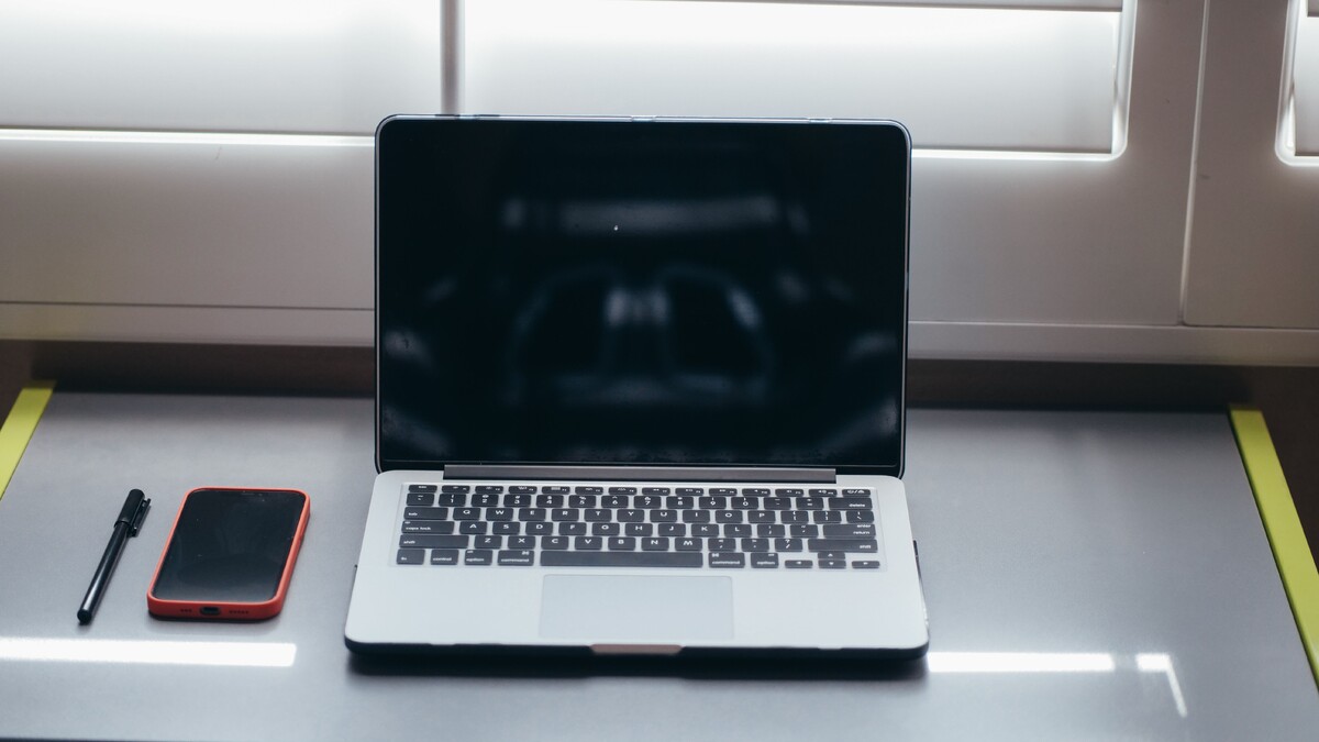 Notebook e celular sobre uma mesa, usados para comunicação digital.