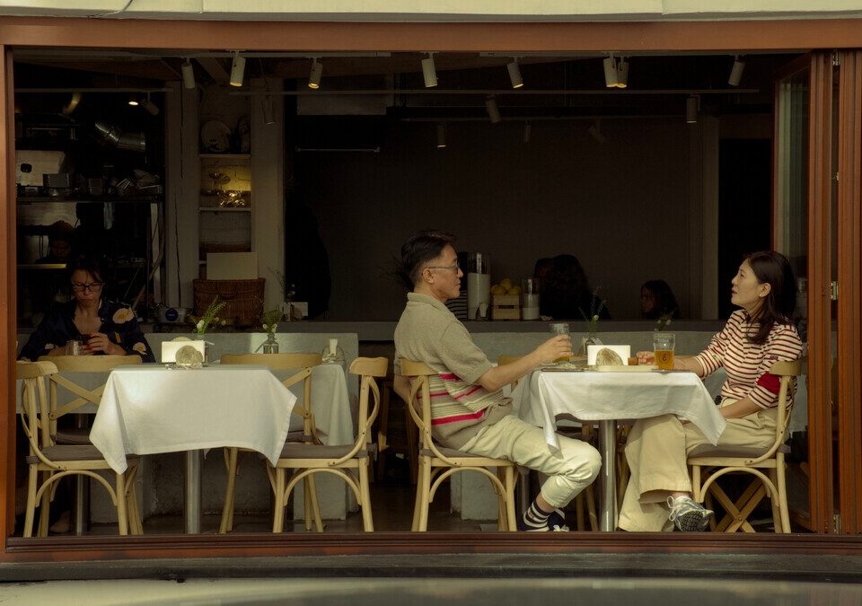 Duas pessoas adultas conversando em uma mesa de café.
