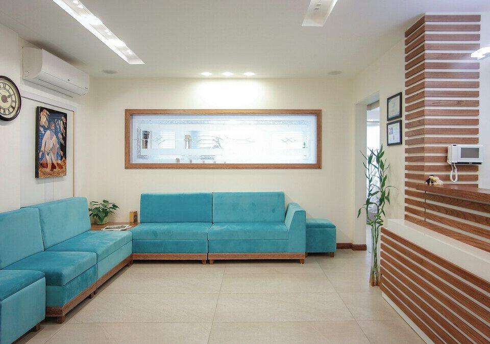 Sala de espera de clínica com sofá azul e planta