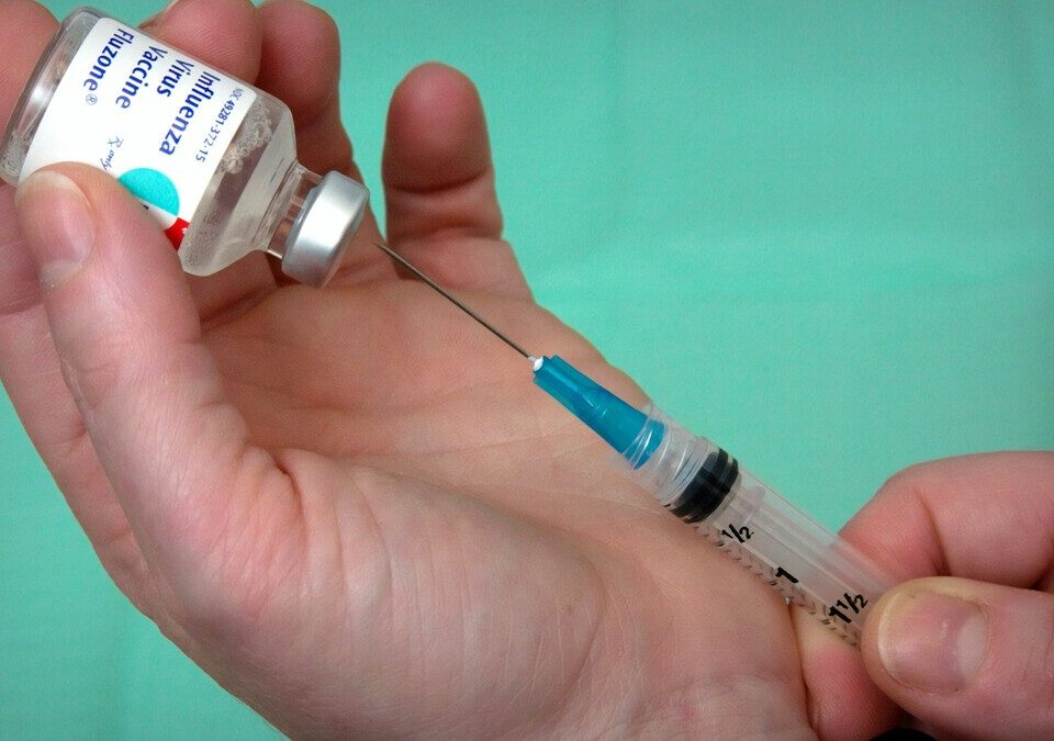 Profissional de saúde aspira dose de vacina de um frasco com seringa