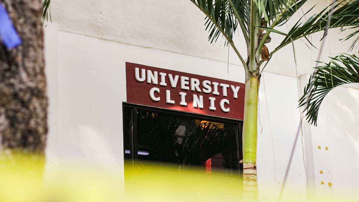 O que a fachada de uma clínica transmite ao paciente? Entrada de clínica universitária com placa vermelha e letras brancas