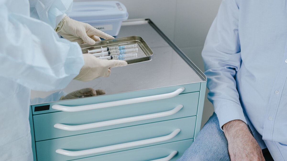 Pneumo 20 no SUS para 85+: quem pode tomar e quais doses valem Profissional de saúde com luvas segura bandeja com seringas sobre carrinho hospitalar