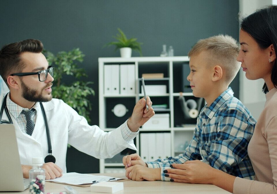 Médico examinando um menino com a mãe ao lado