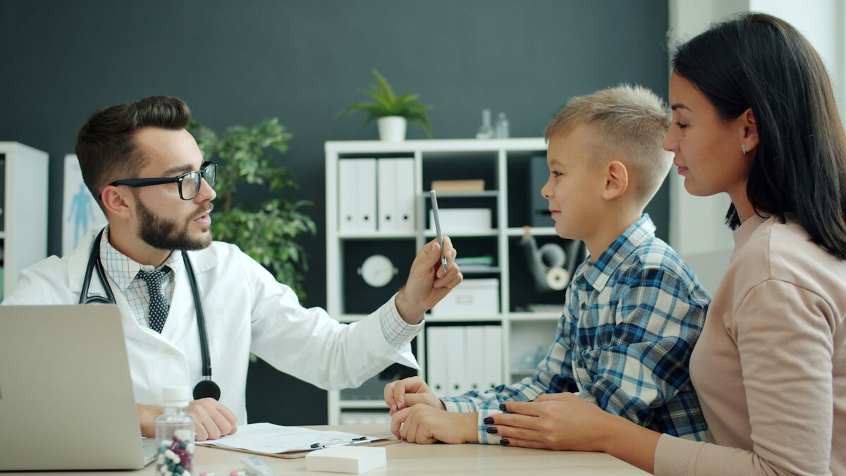 Médico examinando um menino com a mãe ao lado