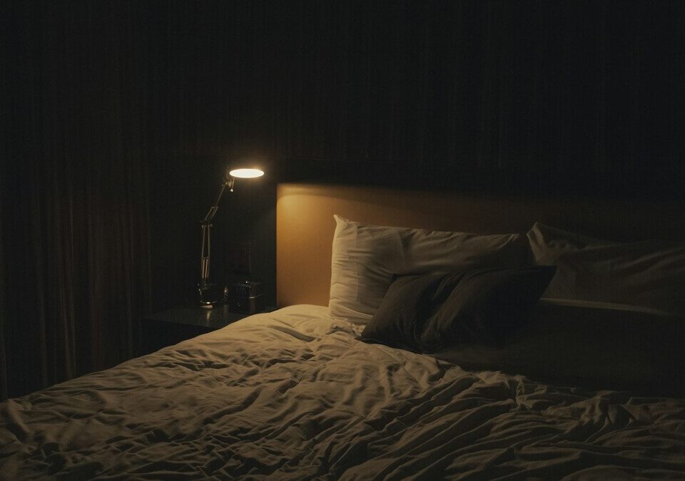 Cama com luminária acesa em um quarto à noite