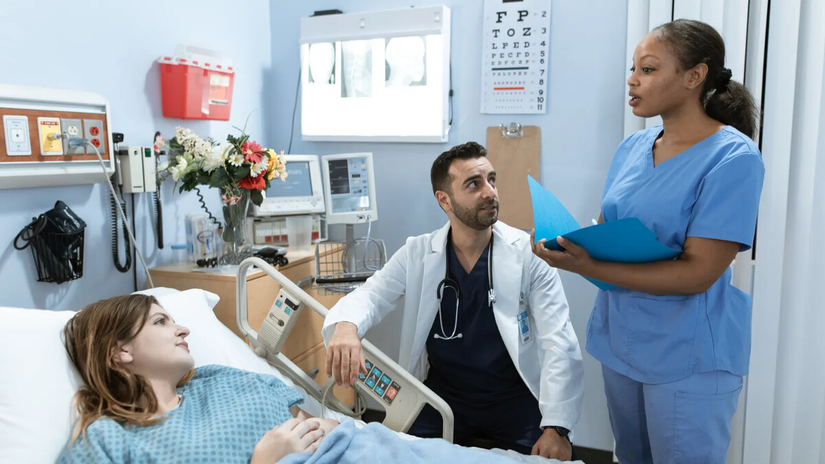 Médicos conversando com paciente em quarto de hospital